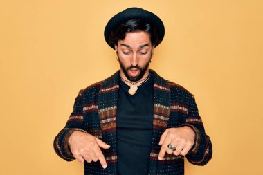 Genç, yakışıklı, bohem, hippi tarzı giyinmiş ve bohem şapkalı bir adam. İlan veren, şaşıran ve ağzı açık olan parmaklarıyla işaret ediyor.