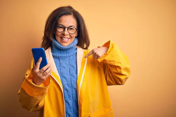 Frau Mittleren Alters Trägt Gelben Regenmantel Mit Smartphone Über Isoliertem — Stockfoto