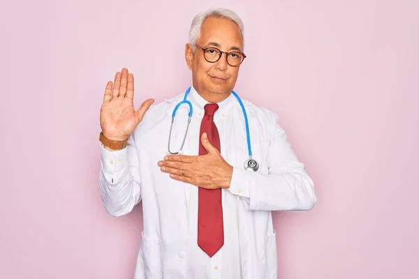 Middle age senior grey-haired doctor man wearing stethoscope and professional medical coat Swearing with hand on chest and open palm, making a loyalty promise oath