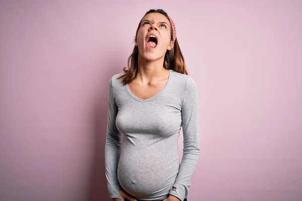 孤立したピンクの背景に赤ちゃんを期待して妊娠している若い美しいティーンエイジャーの女の子は怒りで叫んで フラストレーションと激怒叫んで怒っています 激怒と積極的な概念 — ストック写真
