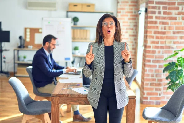 Middelbare Leeftijd Mooie Zakenvrouw Dragen Jas Bril Staan Kantoor Verbaasd — Stockfoto