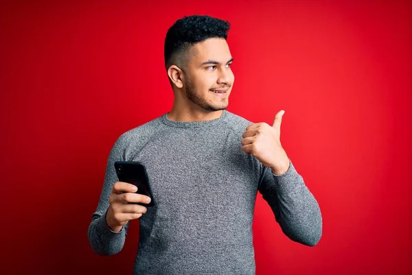 Young Handsome Man Having Conversation Using Smartphone Red Background Pointing — Stock Photo, Image