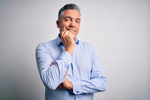 Middle age handsome grey-haired business man wearing elegant shirt over white background looking confident at the camera with smile with crossed arms and hand raised on chin. Thinking positive.