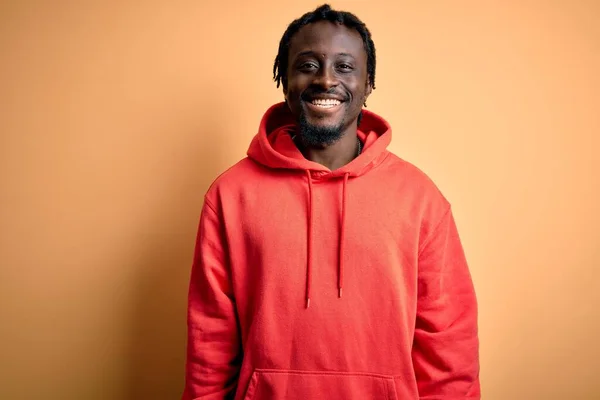 Young african american sporty man wearing sweatshirt with hoodie over yellow background with a happy and cool smile on face. Lucky person.