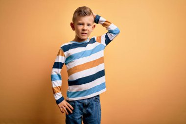 Küçük, beyaz, mavi gözlü, sarı arka plan karışıklığı üzerine renkli çizgili gömlek giyen, soru soran genç bir çocuk. Şüpheyle kararsız, kafa kafaya düşünerek. Düşünceli kavram.