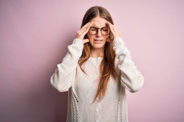 Genç, güzel, kızıl saçlı bir kadın pembe arka planda gözlük ve süveter giyiyor. Baş ağrısı çekiyor çünkü stresten. Migren ağrısı..