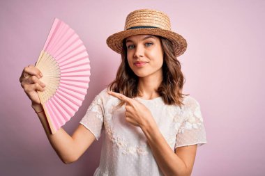 Genç sarışın moda kızı sıcak bir yaz gününde ahşap İspanyol el yelpazesi kullanıyor.