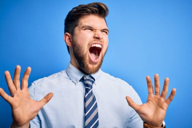 Sarışın, sakallı, mavi gözlü, şık gömlekli ve kravatlı genç bir işadamı. Deli gibi ayakta duruyor, bağırıyor, agresif bir ifade ve kollarla bağırıyor. Hayal kırıklığı konsepti.