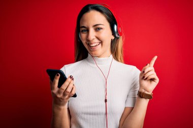 Genç, güzel, esmer, müzik dinleyen akıllı telefon ve kulaklık kullanan bir kadın. Bir fikir veya soru işareti ile şaşırmış, mutlu yüzlü, bir numara.