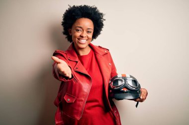 Kıvırcık saçlı, motosiklet kasklı, neşeli gülümsemeli, yardım eli uzatan ve kabul gören Afro-Amerikan motosikletli genç bir kadın..