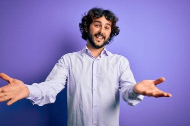 Mor arka planda duran sakallı, yakışıklı iş adamı gülümseyen, yardım eli uzatan ve kabul gören biri..