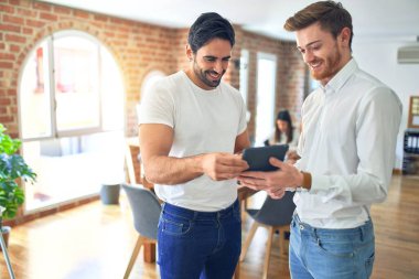İşçiler mutlu gülümsüyor. Yüzünde gülümsemeyle ayakta durup ofiste tablet kullanarak birlikte çalışmak.