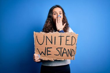 Güzel aktivist kadın elinde bayrak, mavi arka planda birleşik bir mesaj tutuyor. Ağzı kapalı, hata yaptığı için utanmış, korku ifadesi, sessizlikten korkmak, gizli bir kavram.
