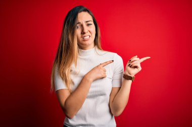 Mavi gözlü, güzel, beyaz tişörtlü, kırmızı arka planlı bir kadın. Endişeli ve gergin. Endişeli ve şaşırmış bir yüz ifadesi var.