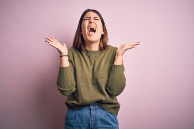 İzole edilmiş pembe arka plan üzerinde duran genç ve güzel bir kadın kollarını kaldırmış ve gözlerini kapatmış heyecanla haykırarak başarının çılgınlığını kutluyor. Kazanan konsept