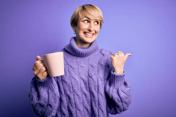 스웨터를 뜨거운 커피를 마시고 엄지손가락을 옆으로 내밀고 얼굴로 금발의 — 스톡 사진