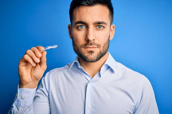 Junger Gutaussehender Mann Mit Zahnausrichterzahnkorrektur Vor Blauem Hintergrund Und Selbstbewusstem — Stockfoto