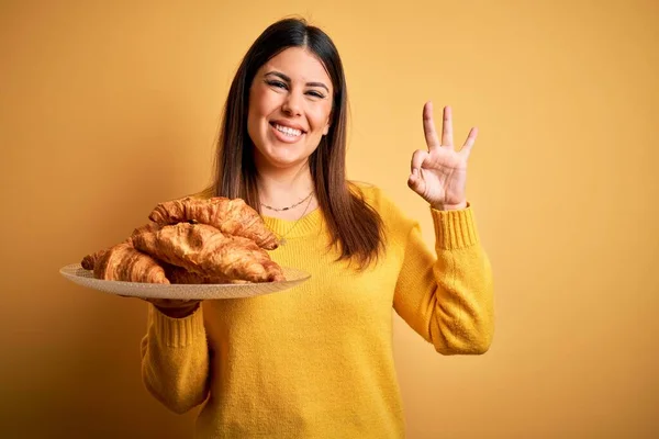 Jovem Bela Mulher Segurando Francês Croissant Pastelaria Sobre Fundo Amarelo — Fotografia de Stock