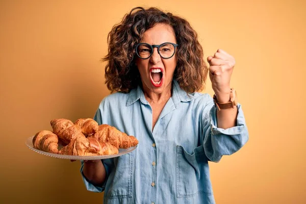 Krásná Žena Středního Věku Drží Talíř Croissanty Přes Izolované Žluté — Stock fotografie