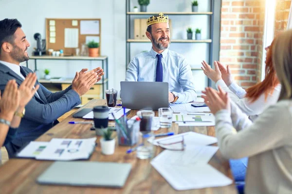 Group of business workers smiling happy and confident. Working together with smile on face applauding one of them wearing king crown at the office