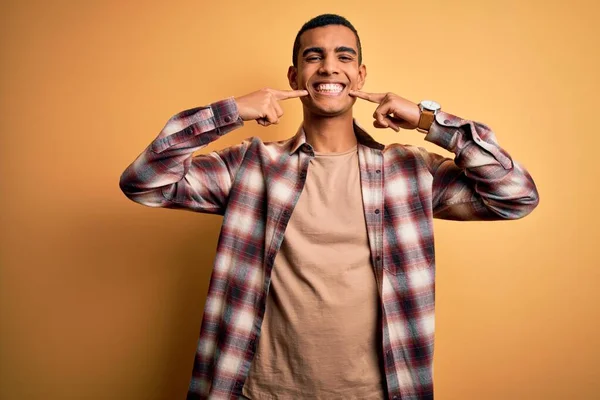 年轻英俊的非洲裔美国男人穿着休闲装 站在黄色的背景上 笑容满面 用手指 牙齿和嘴指尖 牙齿健康概念 — 图库照片
