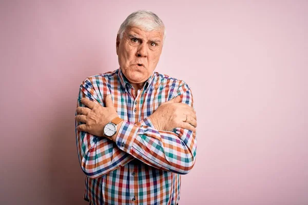 Senior handsome hoary man wearing casual colorful shirt over isolated pink background shaking and freezing for winter cold with sad and shock expression on face