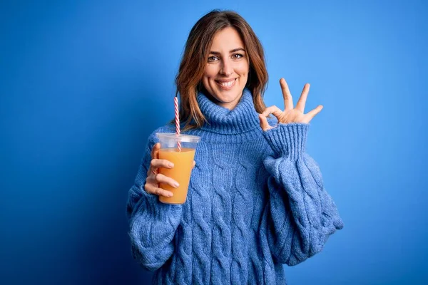 Young Beautiful Brunette Woman Drinking Healthy Orange Juice Blue Background — Stock Photo, Image