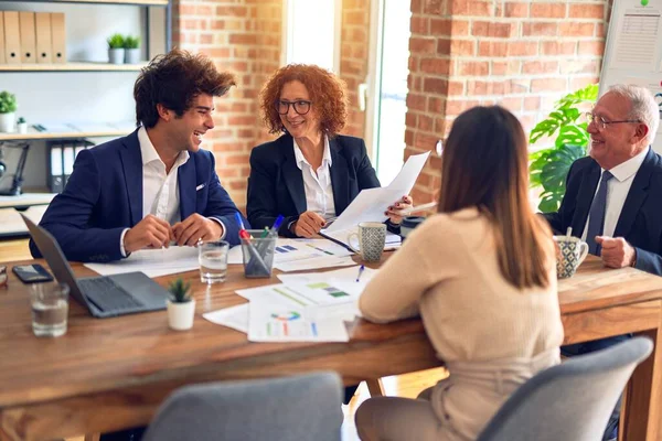 Bir grup iş adamı mutlu ve kendinden emin gülümsüyor. Ofiste birlikte çalışırken gülümseyerek konuşmak..