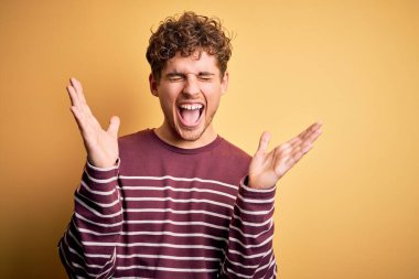 Sarışın, kıvırcık saçlı, sıradan çizgili süveter giyen, başarı için deli ve deli olan genç, kolları havada ve gözleri kapalı heyecanlı bir şekilde kutlama yapan yakışıklı bir adam. Kazanan konsept