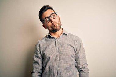 Zarif bir gömlek ve gözlük takan yakışıklı genç adam izole edilmiş beyaz arka planda dudaklı balık suratı yapıyor, çılgınca ve komik bir jest. Komik ifade.