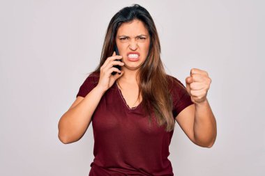 Genç İspanyol kadının akıllı telefondan konuşması izole bir arka planda sinirlenmiş ve hayal kırıklığına uğramış öfkeyle bağırması ve el kaldırarak bağırması, öfke konsepti.