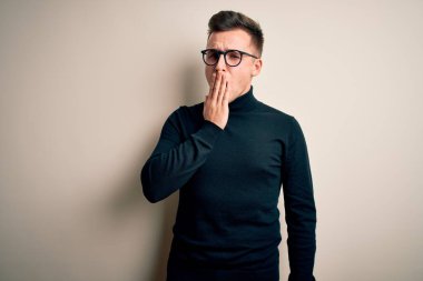 Gözlük takan yakışıklı beyaz bir adam ve izole edilmiş arka planda sıradan bir süveter giymekten sıkılmış, ağzı eliyle kapatmaktan bıkmış. Huzursuz ve uykulu..