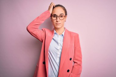 Ceket ve gözlük takan genç ve güzel bir iş kadını soyutlanmış pembe arka plan karışıklığı ve soru sorulmasını merak ediyor. Şüpheyle kararsız, kafa kafaya düşünerek. Düşünceli kavram.