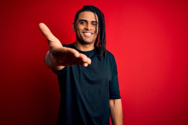 Rastgele tişörtler giyen Afro-Amerikan genç, yakışıklı afro adam dostça bir selamlama ve hoş geldin hediyesi olarak gülümsüyor. Başarılı bir iş..