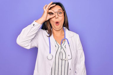 Mor arka planda steteskop ve tıbbi ceket giyen profesyonel doktor kadın şaşırmış yüz ifadesiyle şaşırmış, parmaklarından bakan gözler. İnançsız ifade.