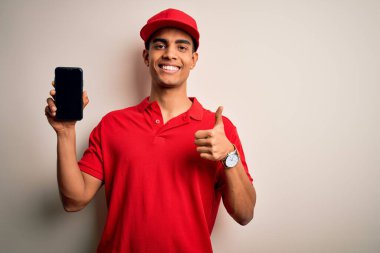 Yakışıklı Afro-Amerikan teslimatçı elinde akıllı telefonla ekrandaki uygulamayı gösteriyor. Gülümsüyor ve gülümsüyor. İşaret veriyor.