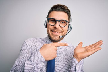 Genç çağrı merkezi operatörü mavi gözlü, gözlüklü, kulaklıklı, hayrete düşmüş ve kameraya gülümseyen bir iş adamı..