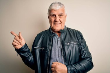 Üst düzey yakışıklı beyaz gömlekli ve ceketli, soyutlanmış beyaz arka planda, yüzünde kocaman bir gülümseme, eli ve parmağı kameraya bakan yaşlı ve beyaz adam..