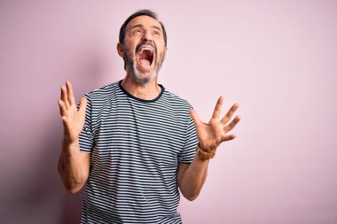 Sıradan çizgili tişört giyen, orta yaşlı, beyaz bir adam pembe arka planda dikiliyor. Deli gibi bağırıyor, agresif bir ifade ve kollarla bağırıyor. Hayal kırıklığı konsepti.