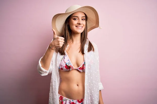 아름다운 비키니를 모자를 분홍색 위에서 엄지손가락을 손으로 휴가중이다 카메라 표정을 — 스톡 사진
