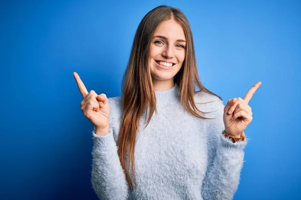 年轻美丽的红头发女人穿着休闲衫 披着孤立的蓝色背景 带着自信的微笑 手指指向不同的方向 广告的复制空间 — 图库照片