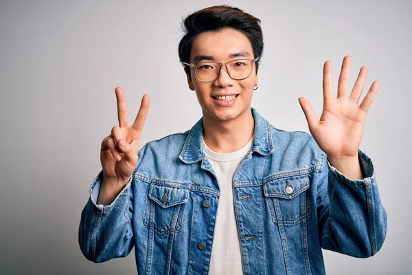 Mladý Pohledný Číňan Muž Džínové Bundě Brýle Bílém Pozadí Ukazuje — Stock fotografie
