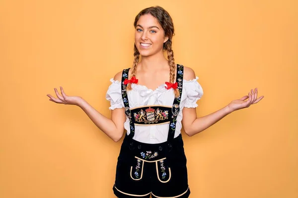 年轻美丽的金发德国女人 蓝眼睛 身穿传统的十月节礼服 微笑着张开双手 展示和宣传比较与平衡 — 图库照片