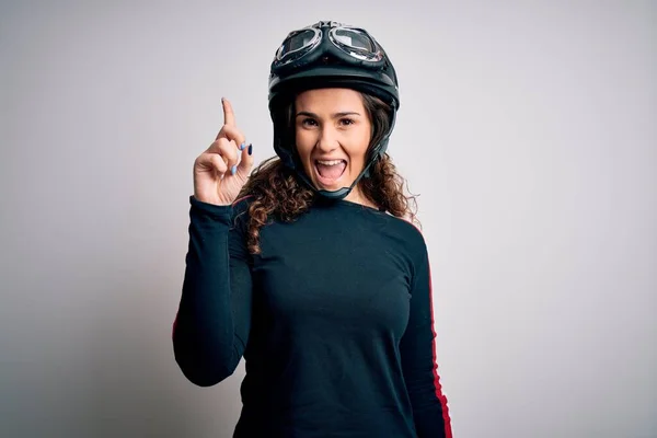 白い背景の上に元ヘルメットを身に着けている巻き毛を持つ美しいオートバイの女性は 成功したアイデアで指を指しています 興奮し 第一番 — ストック写真