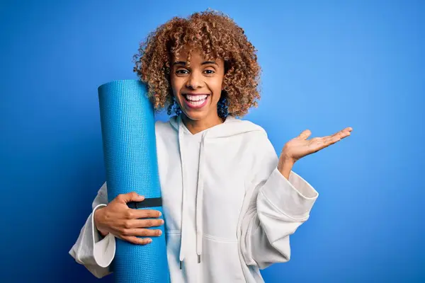 Junge Afrikanisch Amerikanische Sportlerin Hält Yogamatte Über Isoliertem Blauem Hintergrund — Stockfoto