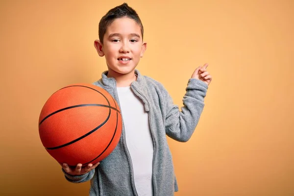 Jovem Garoto Brincando Com Bola Basquete Sobre Fundo Amarelo Isolado — Fotografia de Stock