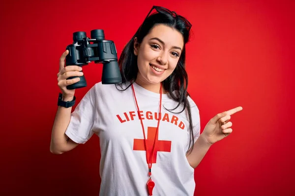 Junge Rettungsschwimmerin Schutzausrüstung Mit Fernglas Über Rotem Hintergrund Sehr Glücklich — Stockfoto