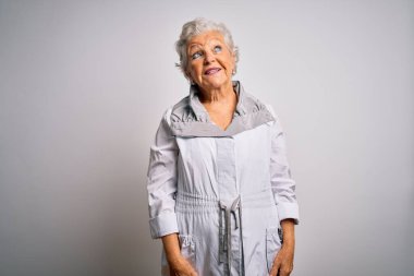 Son sınıf güzeli, gri saçlı, sıradan bir ceket giyen, beyaz arka planda duran, yüzünde gülümseme, doğal bir ifade olan bir kadın. Kendinden emin gülen.