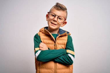 Mavi gözlü, kışlık ceket giyen ve kollarını kavuşturup kameraya gülümseyen neşeli gözlüklü beyaz bir çocuk. Pozitif kişi.