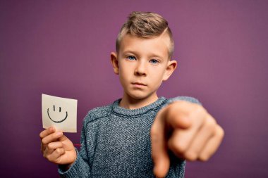 Küçük beyaz bir çocuk kağıtta gülen suratını gösteriyor. Kamerayı işaret eden mutlu bir mesaj olarak. Ve sen, el işareti, ön taraftan olumlu ve kendinden emin bir hareket.